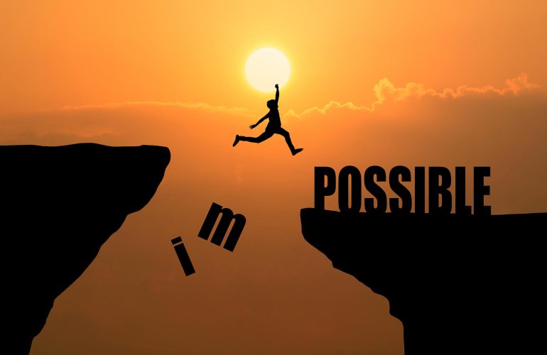 Man jumping over impossible or possible over cliff on sunset bac